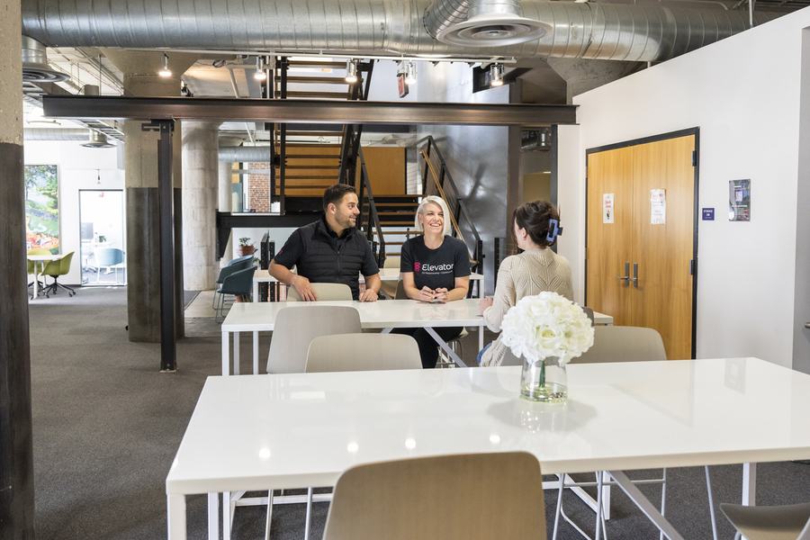 Members working at the big tables on the coworking floor at Elevator Omaha